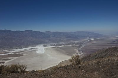 Aerial view of land and mountains against clear blue sky