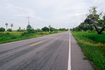 Road by trees against sky