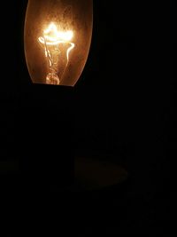 Close-up of illuminated light bulb against black background