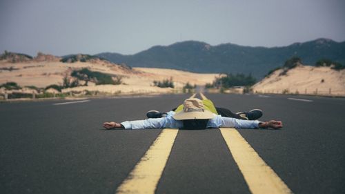 Man lying on road against mountain