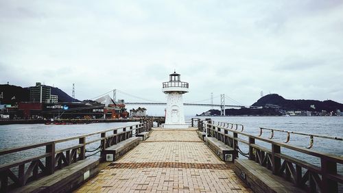 View of pier at harbor against cloudy sky