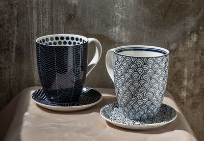 Close-up of coffee cup on table against wall at home