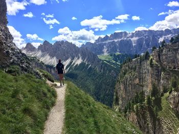 Woman walking on road amidst mountains against sky