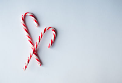 Close up of two candy canes arranged on a plain white background.