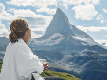 Rear view of woman looking at mountains against sky