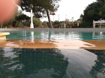 Swimming pool by lake against sky