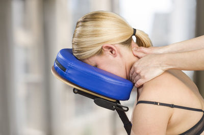 Cropped hands of young woman giving neck massage to mature woman on chair