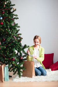 Portrait of girl sitting by christmas tree