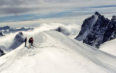 Rear view of mountaineers standing on snowcapped mountains