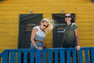 Full length of woman standing against yellow wall