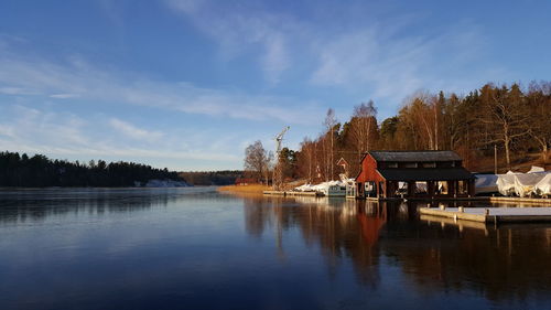 House by lake against sky