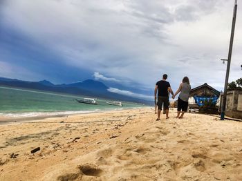 Rear view of people on beach against sky