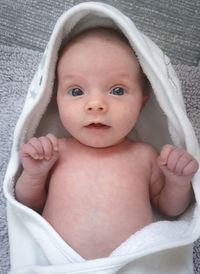 Portrait of cute baby girl lying on bed at home