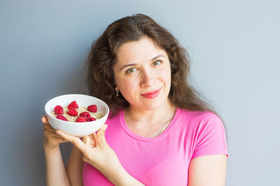 Portrait of smiling woman holding apple against white background