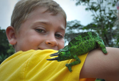 Portrait of boy with jackson chameleon on arm