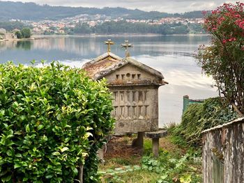 Built structure by lake and buildings against sky