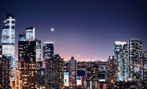 Illuminated buildings in city against sky at night