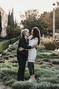 Active senior woman and adult daughter embracing each other outside