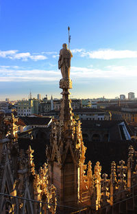 Statue in city against sky