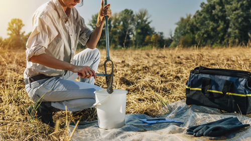 Agronomist collecting soil samples while crouching on field