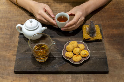 Cropped hands of woman holding coffee on table