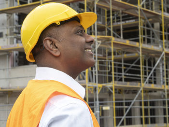 Side view of young man standing against building