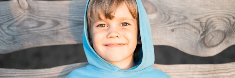 Portrait of face happy smiling candid five year old kid boy in blue hoodie in a hood