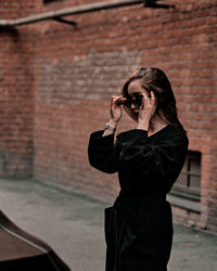 Side view of young man photographing against wall