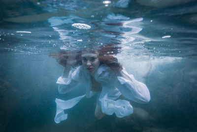 Portrait of young woman swimming underwater in sea