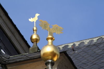 Low angle view of gold sculptures on roof against clear sky