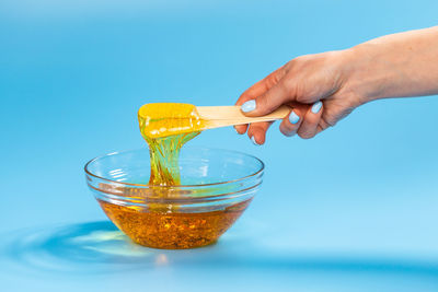 Midsection of person holding drink against blue background