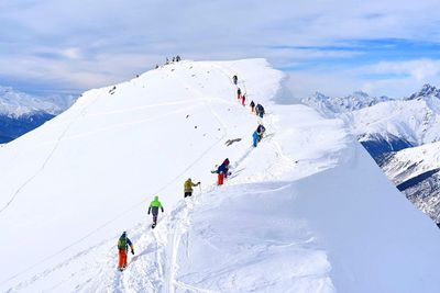 People on snowcapped mountain against sky