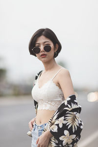 Portrait of sensuous young woman wearing sunglasses while standing on road