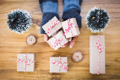 Cropped hands of man holding christmas presents on wooden table