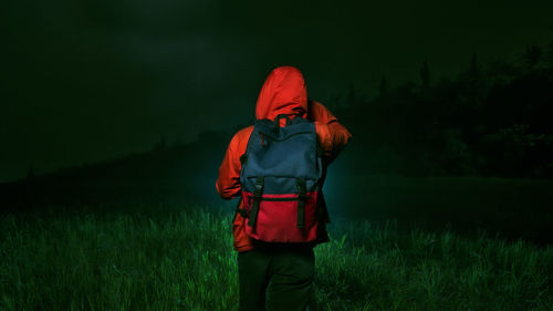 Rear view of woman walking on field at night