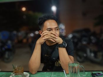 Portrait of a man drinking glass on table at restaurant