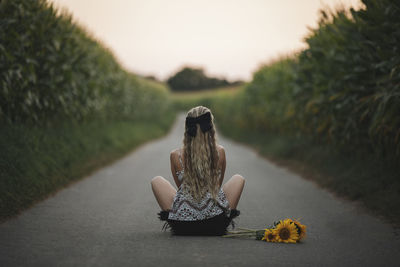 Rear view of woman sitting on road