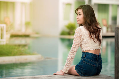 Side view of young woman sitting outdoors