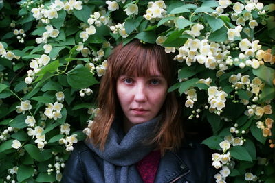 Close-up portrait of young woman amidst flower plants