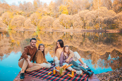 Cheerful family sitting on pier by lake at forest