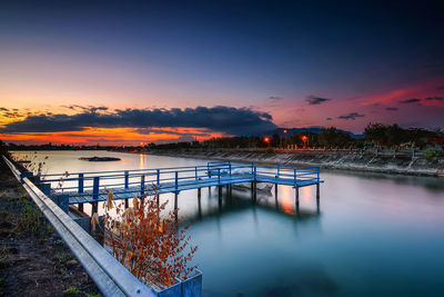 Bridge over river against sky at sunset