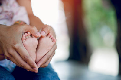 Midsection of mother holding baby feet at home