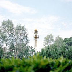 Tower amidst trees and buildings against sky
