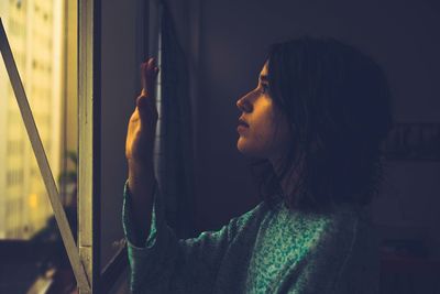 Side view of young woman looking through window