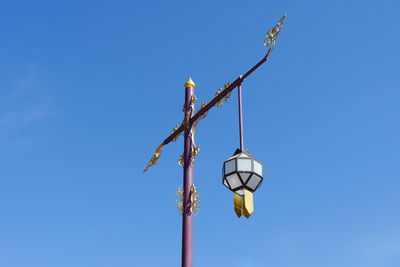 Low angle view of bird hanging against clear blue sky