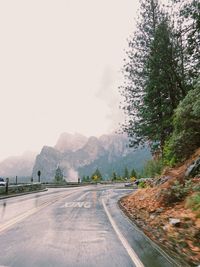 Road by trees against sky