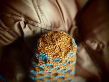 Close-up of woolen mitten on sofa