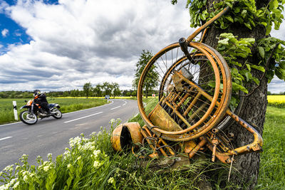 Bicycle on road amidst trees on field against sky