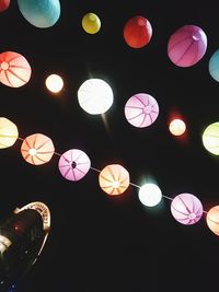 Low angle view of illuminated lanterns hanging against black background