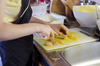 Midsection of woman slicing meat on cutting board